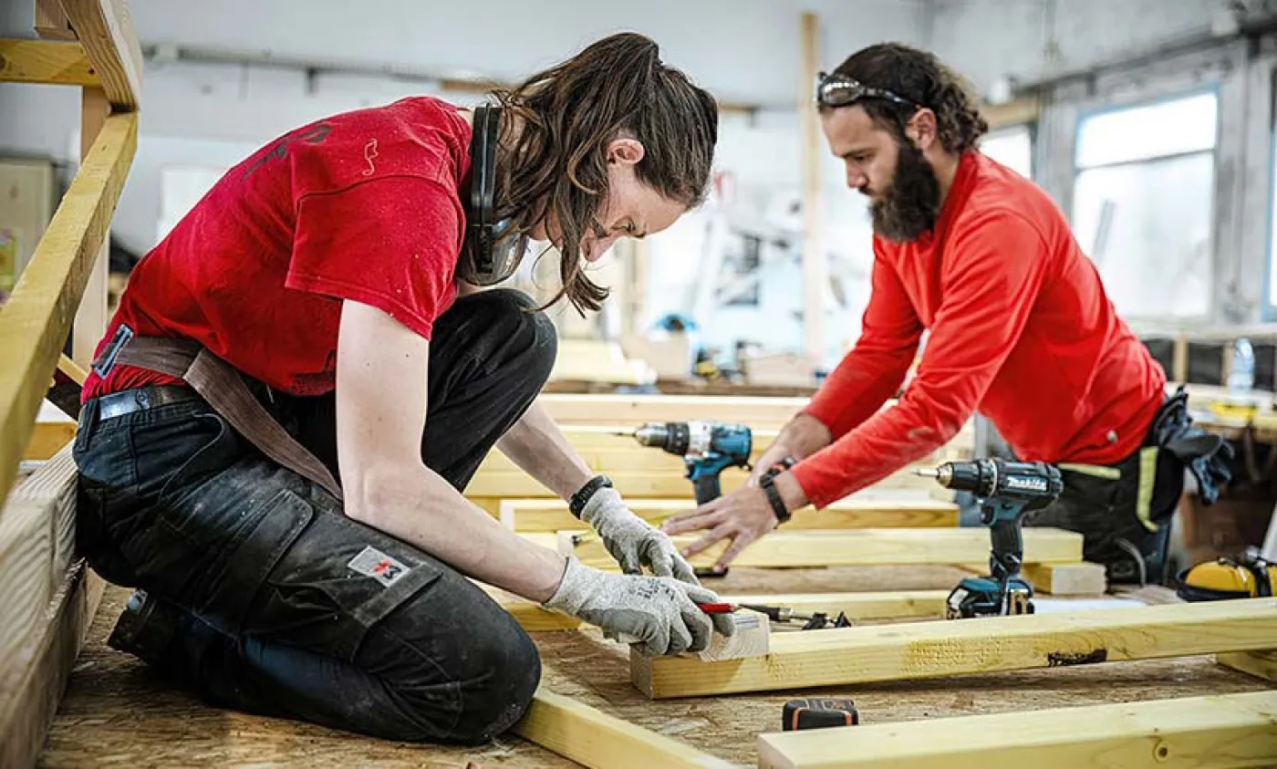 Un homme et une femme travaillent sur une structure en bois