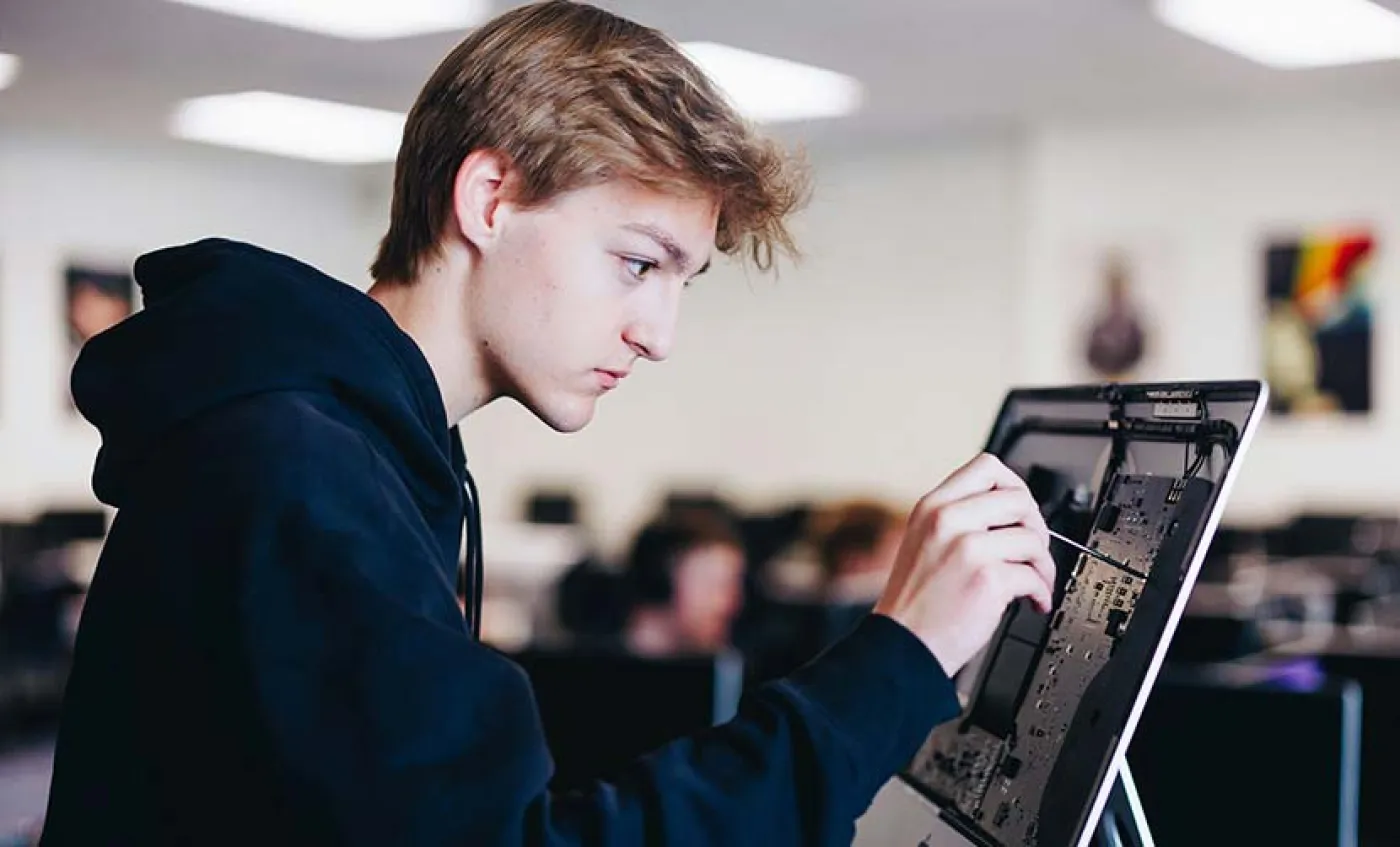 Un jeune stagiaire répare un ordinateur