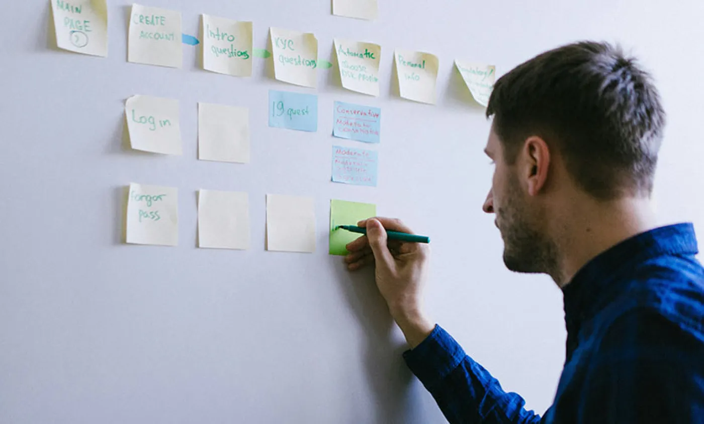 Un homme écrit sur des post-it affichés au mur
