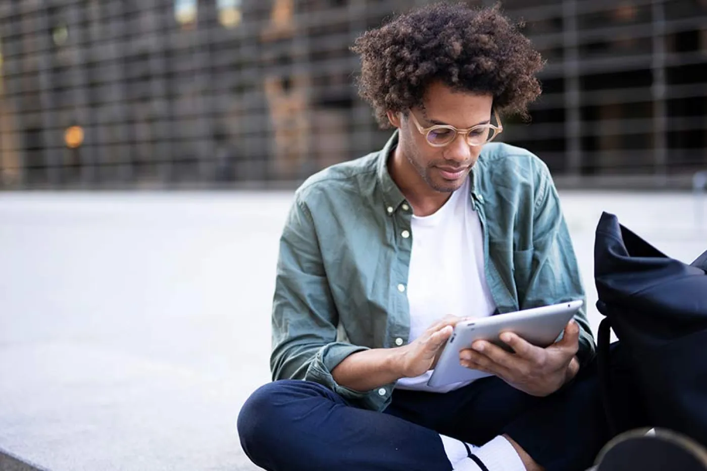 Un étudiant assis dehors regarde une tablette