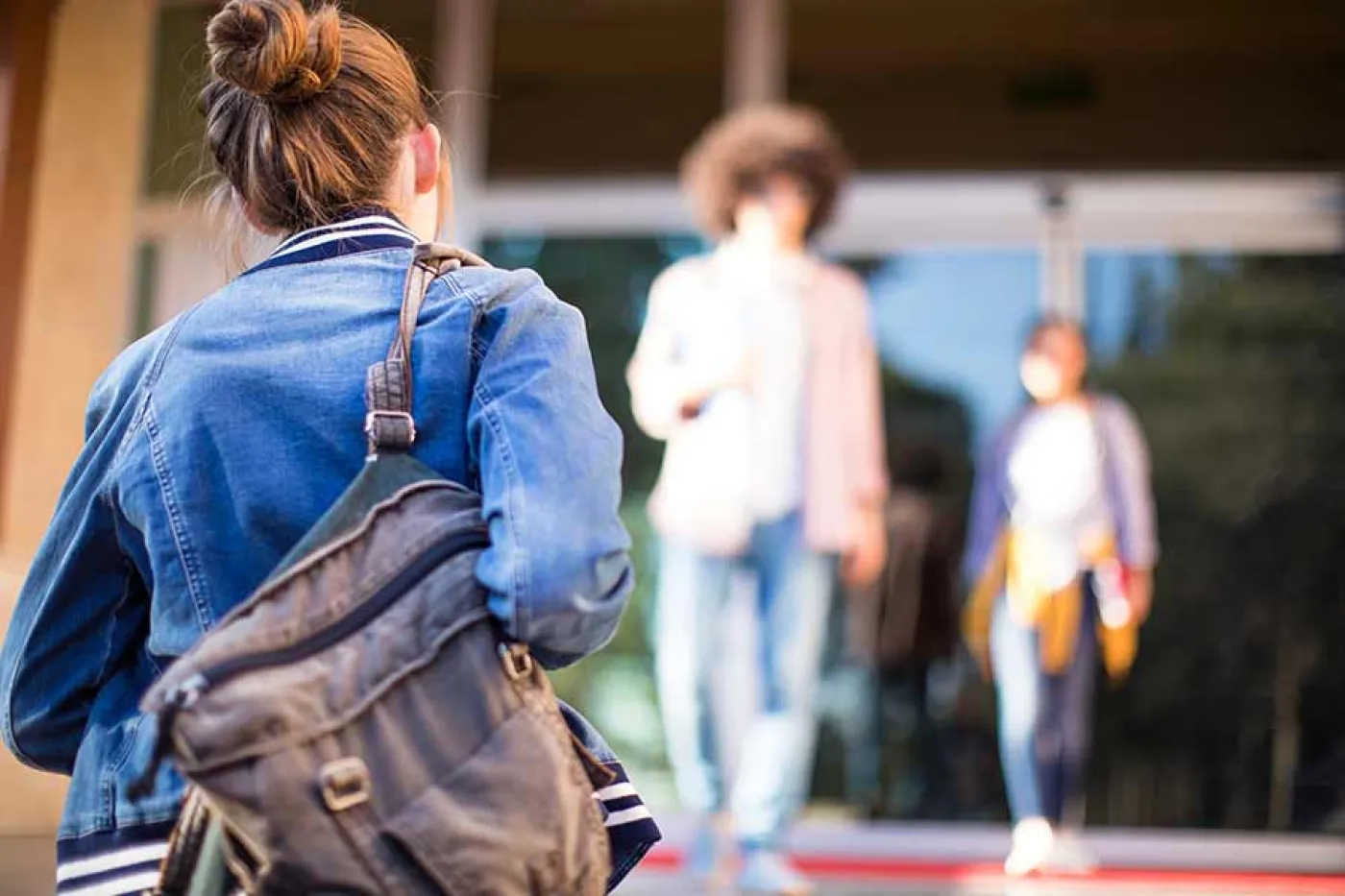 Une étudiante avec un sac à dos monte les marches d'une université