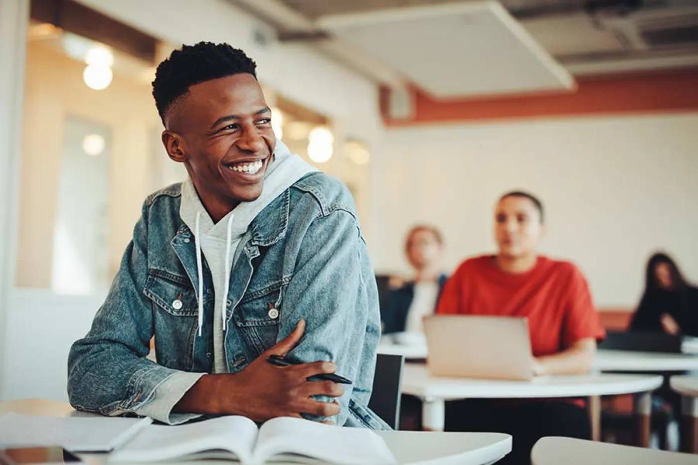 Un élève au premier rang d'une classe sourit en regardant vers la droite