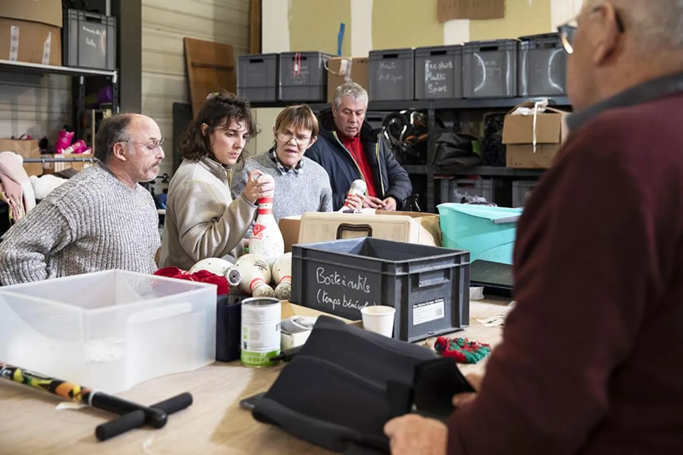Des personnes trient du matériel de sport et le nettoient autour d'une table 