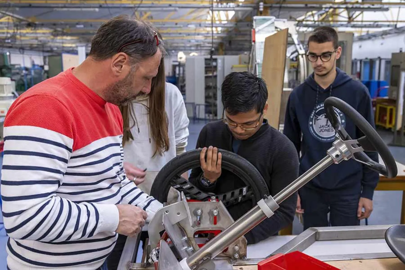 Un enseignant parle avec un groupe d'élèves autour d'un prototype de voiture
