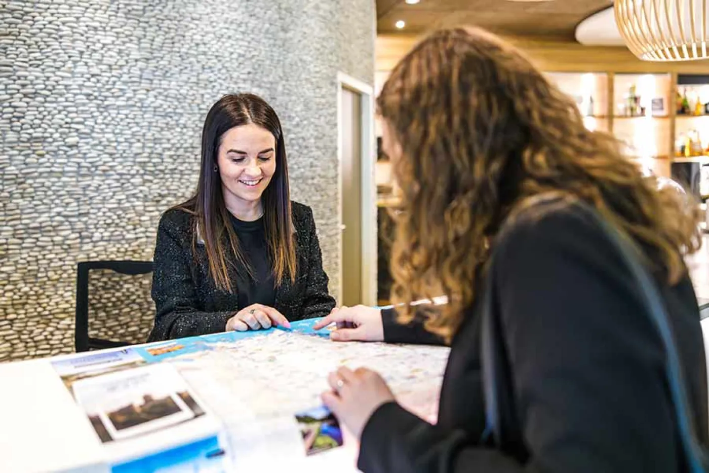 Une réceptionniste derrière son comptoir parle avec une cliente