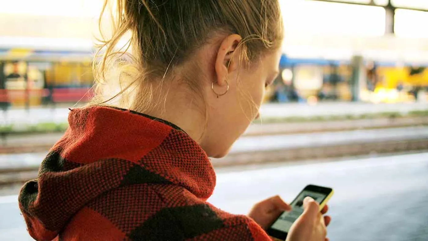Une étudiante regarde son smartphone dans la rue