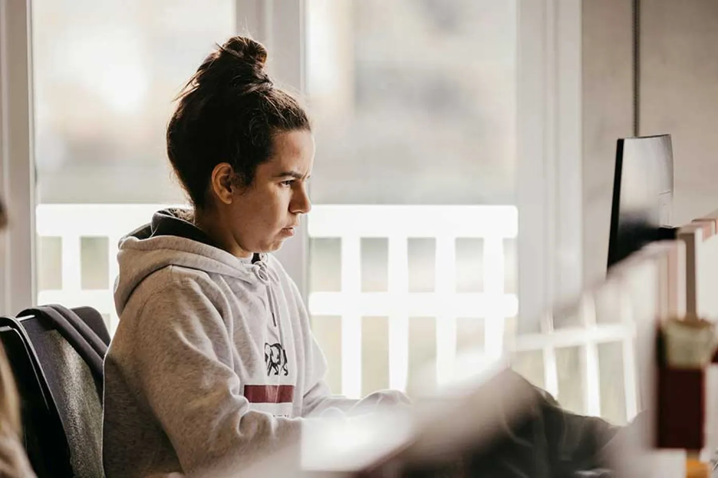 Une lycéenne de profil regarde son ordinateur chez elle