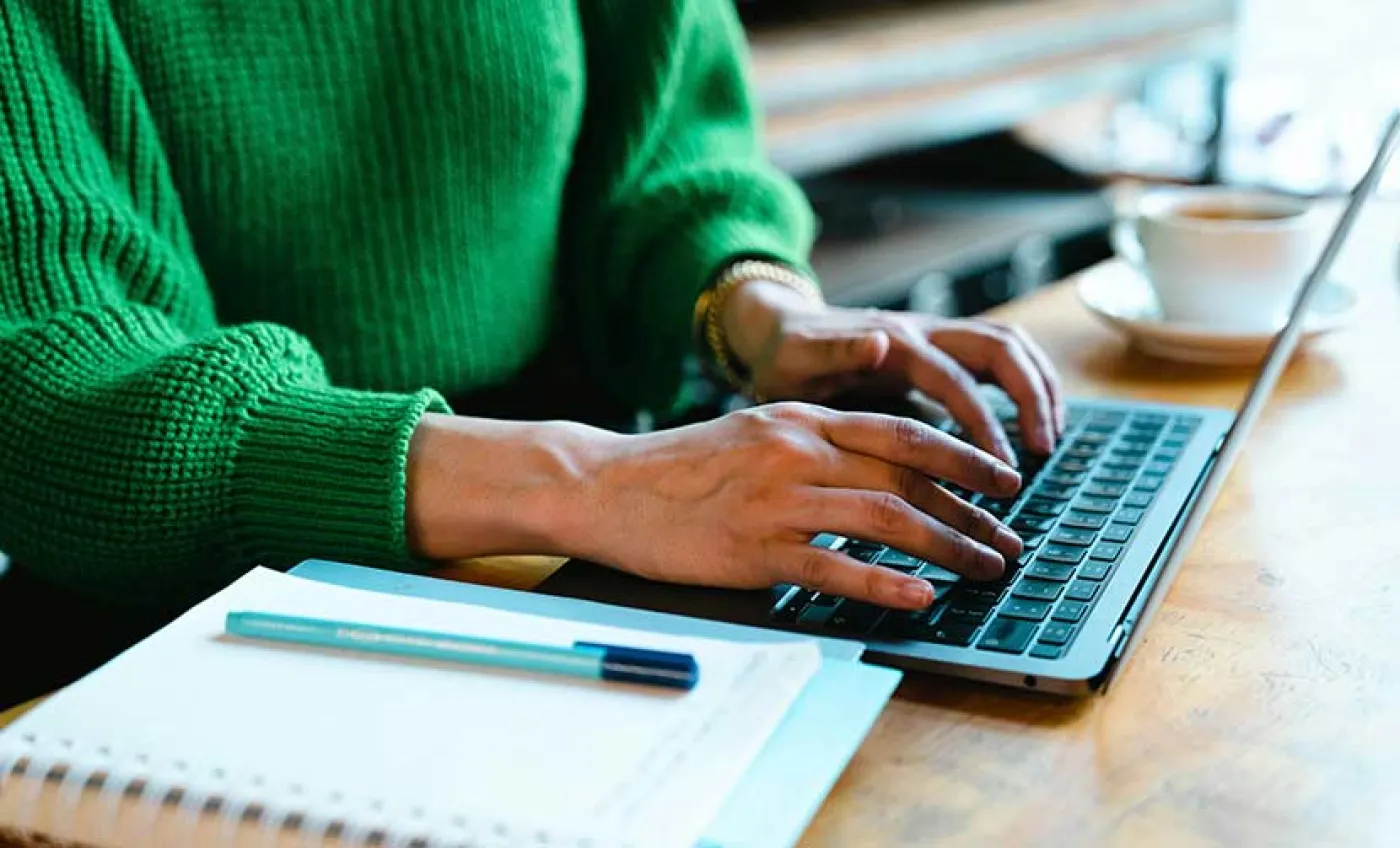 Deux mains de femme tapent sur le clavier d'un ordinateur portable