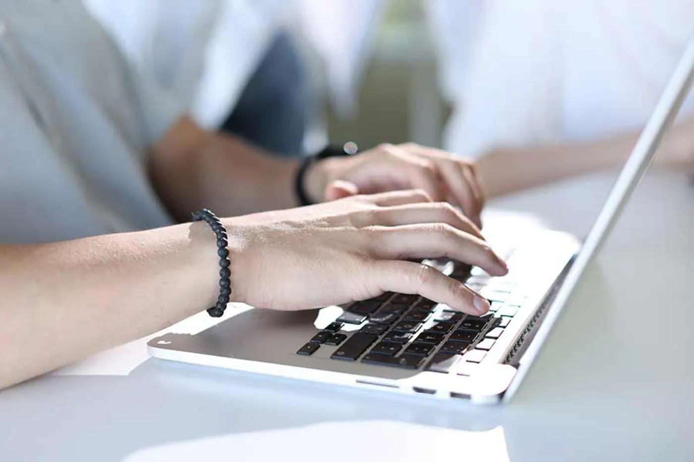 Deux mains tapent sur un ordinateur portable