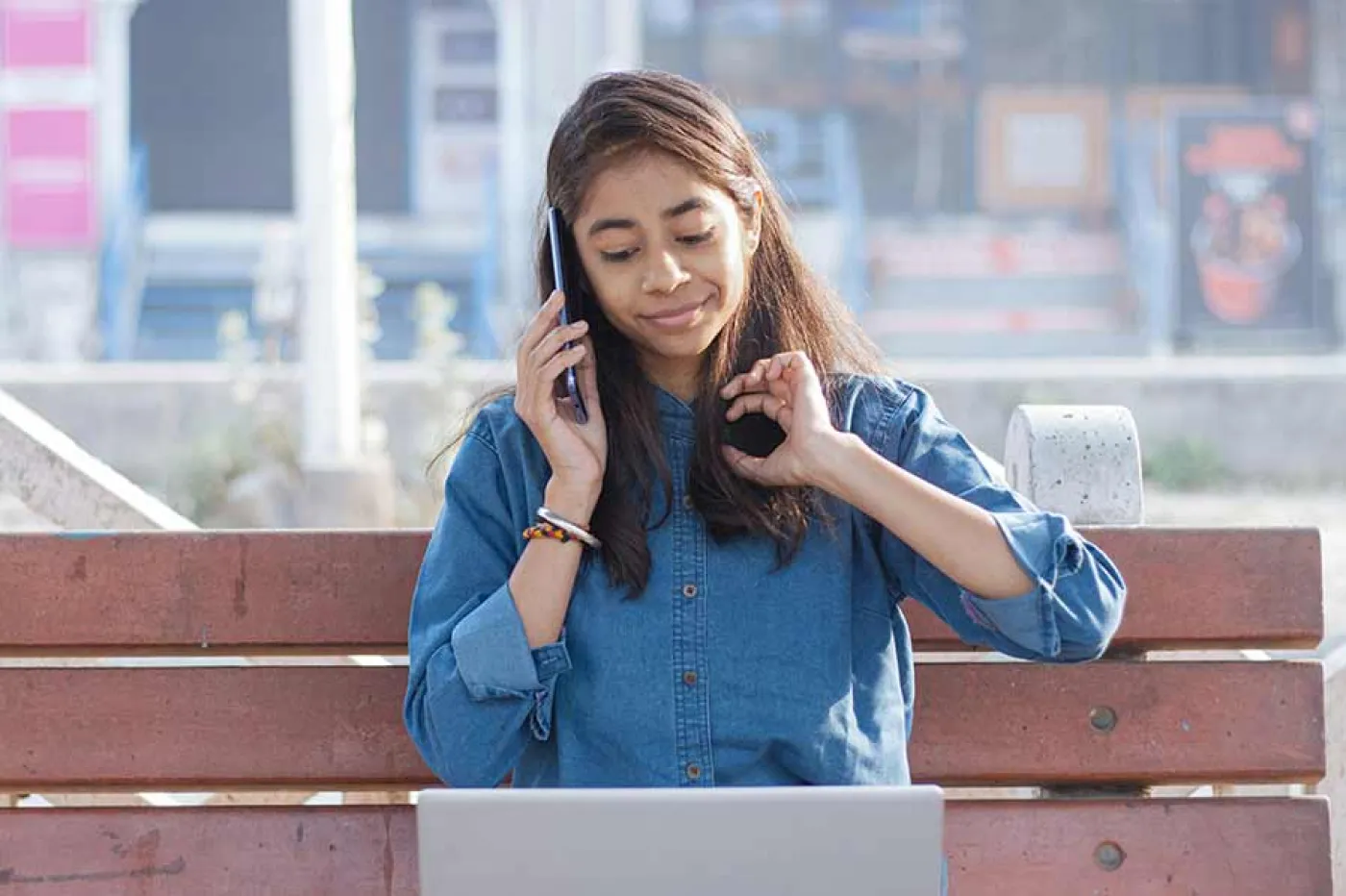 Une étudiante sur un bac téléphone et regarde son ordinateur en même temps