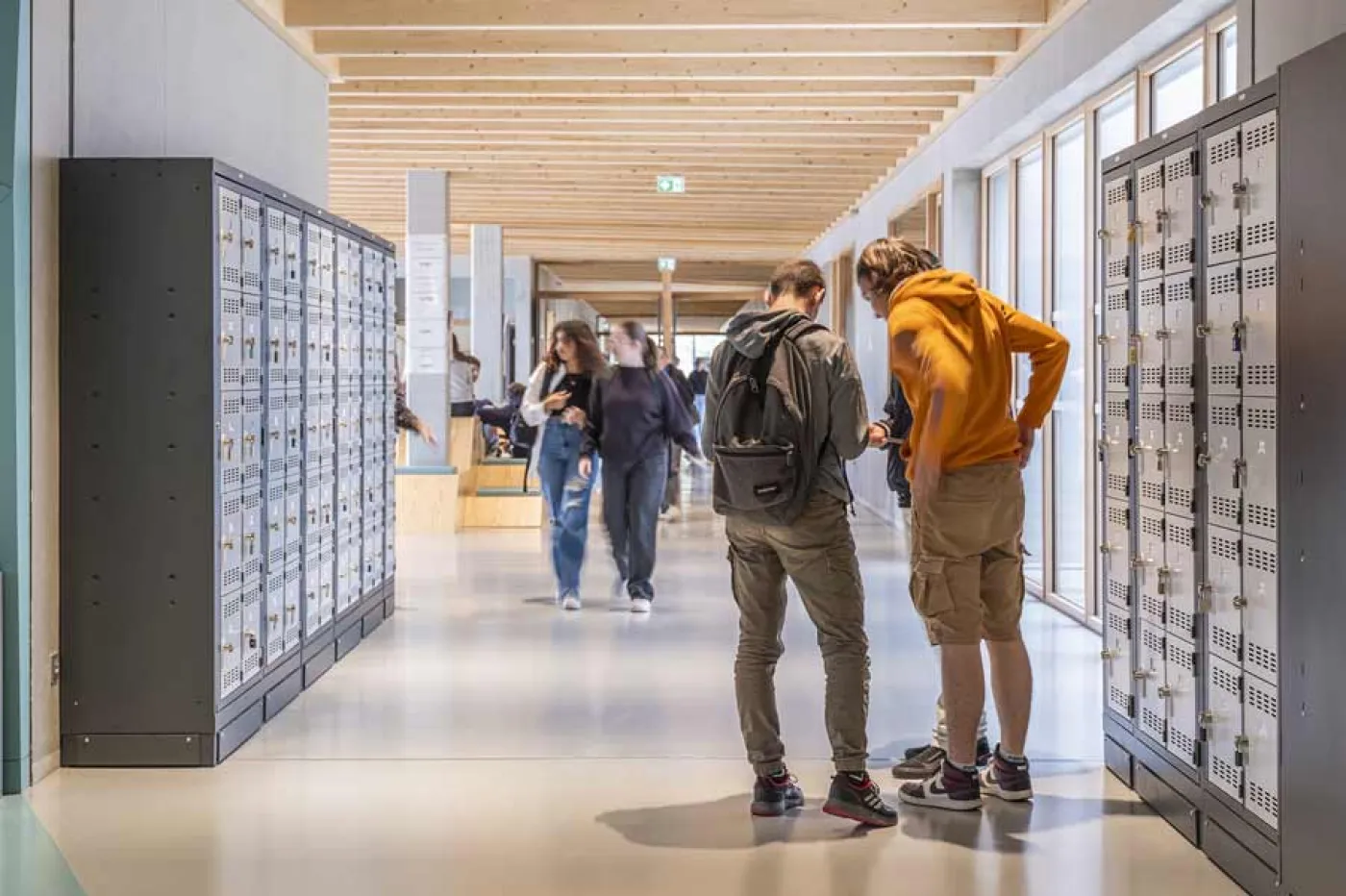 Des élèves parlent ensemble dans un couloir, devant leurs casiers