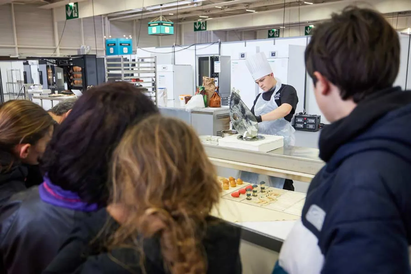 Des élèves regardent un pâtissier travailler à la Compétition des métiers