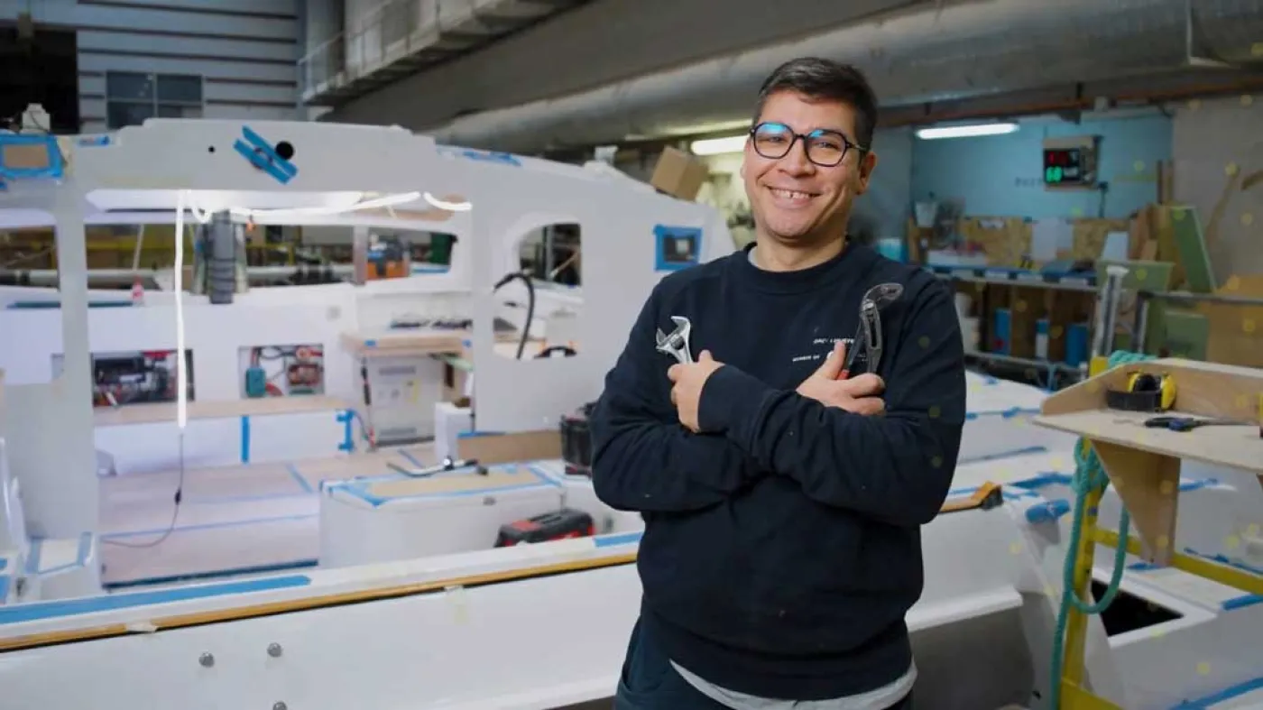 Portrait de Matias avec des outils devant un bateau de plaisance