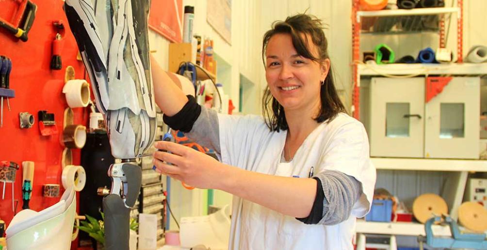 Agathe Le Gourières tient une prothèse de jambe sur l'établi de son atelier