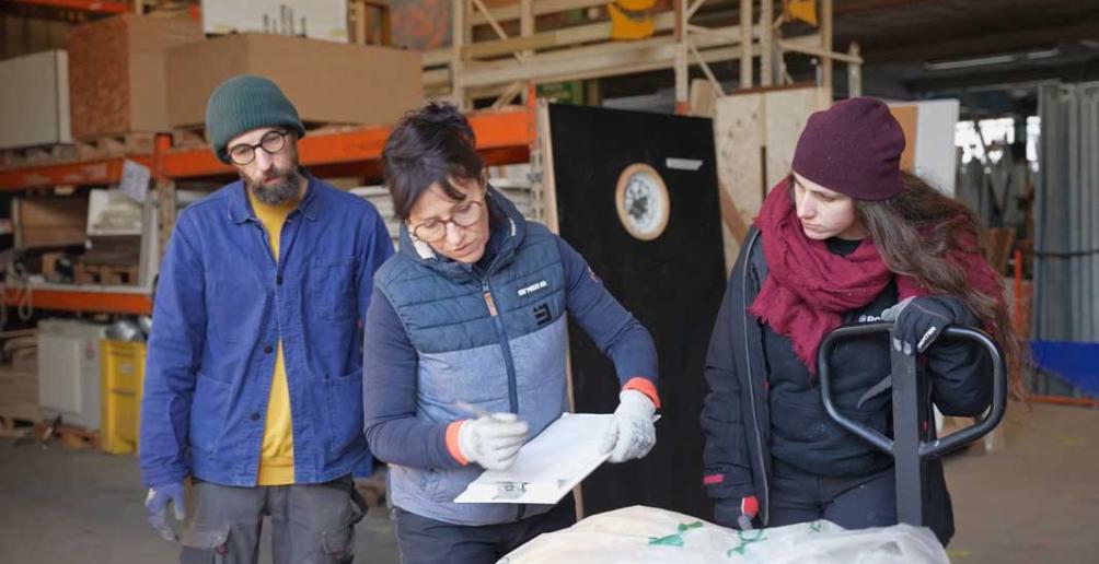 Marie note sur un cahier les références d'une fenêtre qui arrive en ressourcerie