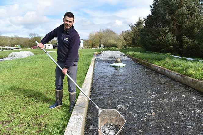 Thomas Tison tient une épuisette au bord d'un bassin