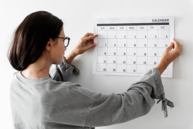 Une jeune femme accroche le programme sur un tableau