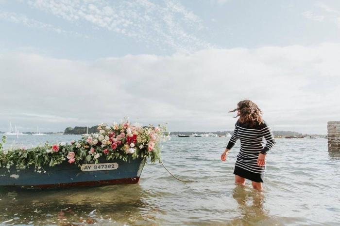 Thiphaine Turluche dans la mer, à côté d'une barque remplie de fleurs