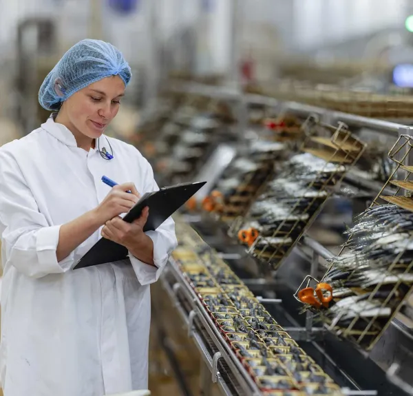 Une cheffe de projet recherche et développement prend des notes face à des rayonnages de sardines