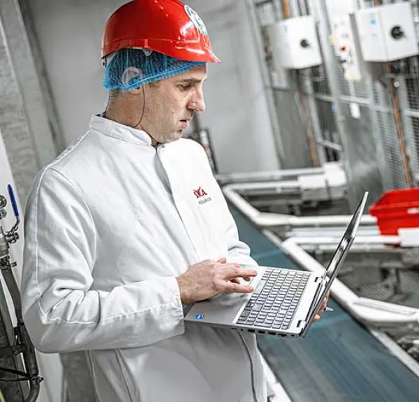 Un ingénieur méthodes regarde son PC portable devant une chaîne de production
