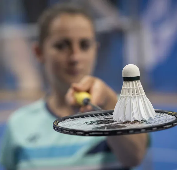 Faustine Noël tient sa raquette de badminton devant elle avec un volant dessus