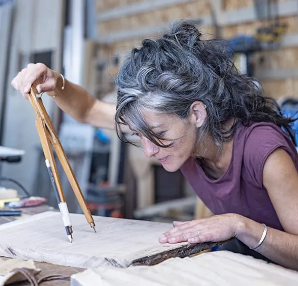 Une ébéniste dessine au compas sur une planche de bois