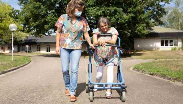 Une monitrice éducatrice se promène aux côtés d'une personne en situation de handicap