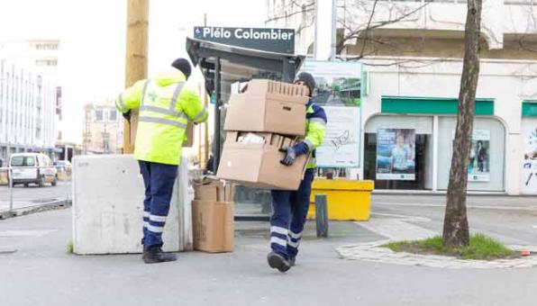 Deux agents de propreté urbaine ramassent des cartons dans une rue
