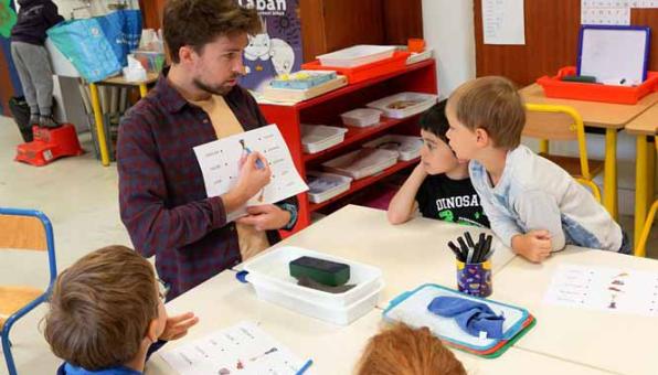 Un professeur montre des mots à des élèves de primaire