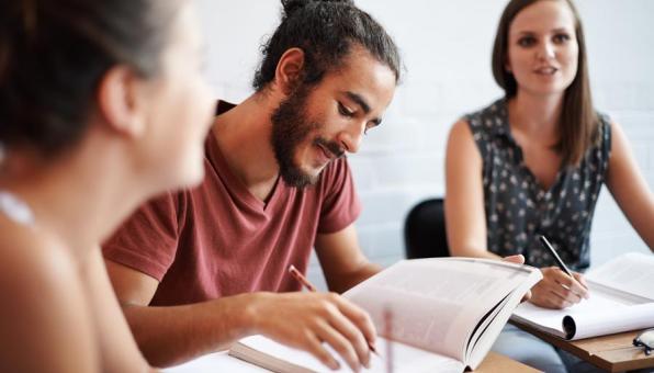 Un étudiant regarde un livre à côté d'une étudiante