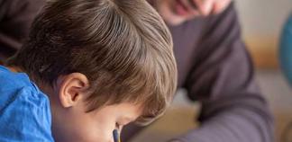 Un professionnel aide un enfant à faire ses devoirs