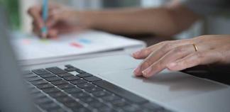 Une personne tape sur un clavier d'ordinateur et regarde un smartphone