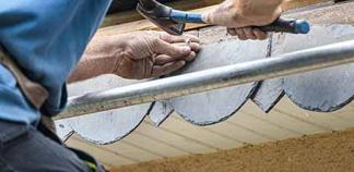 Un couvreur fixe des ardoises sur un toit