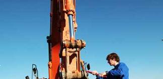 Un homme change le godet d'une pelleteuse