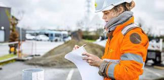 Une cheffe de chantier prend des notes sur un chantier