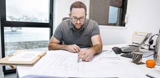 Un conducteur de travaux regarde un plan du chantier à son bureau