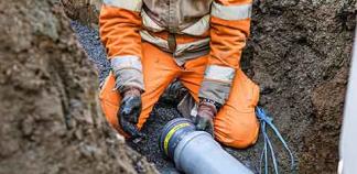 Un professionnel installe une canalisation dans une tranchée