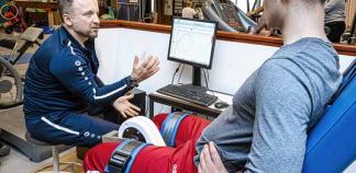 Un professeur en activité physique adaptée donne les consignes de la séance sportive avec un jeune en fauteuil
