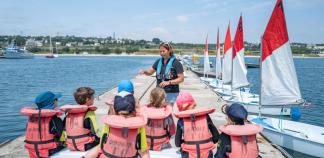 Une éducatrice sportive prépare une sortie en mer avec des enfants.